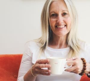 Welcoming image of woman in chair drinking coffee.