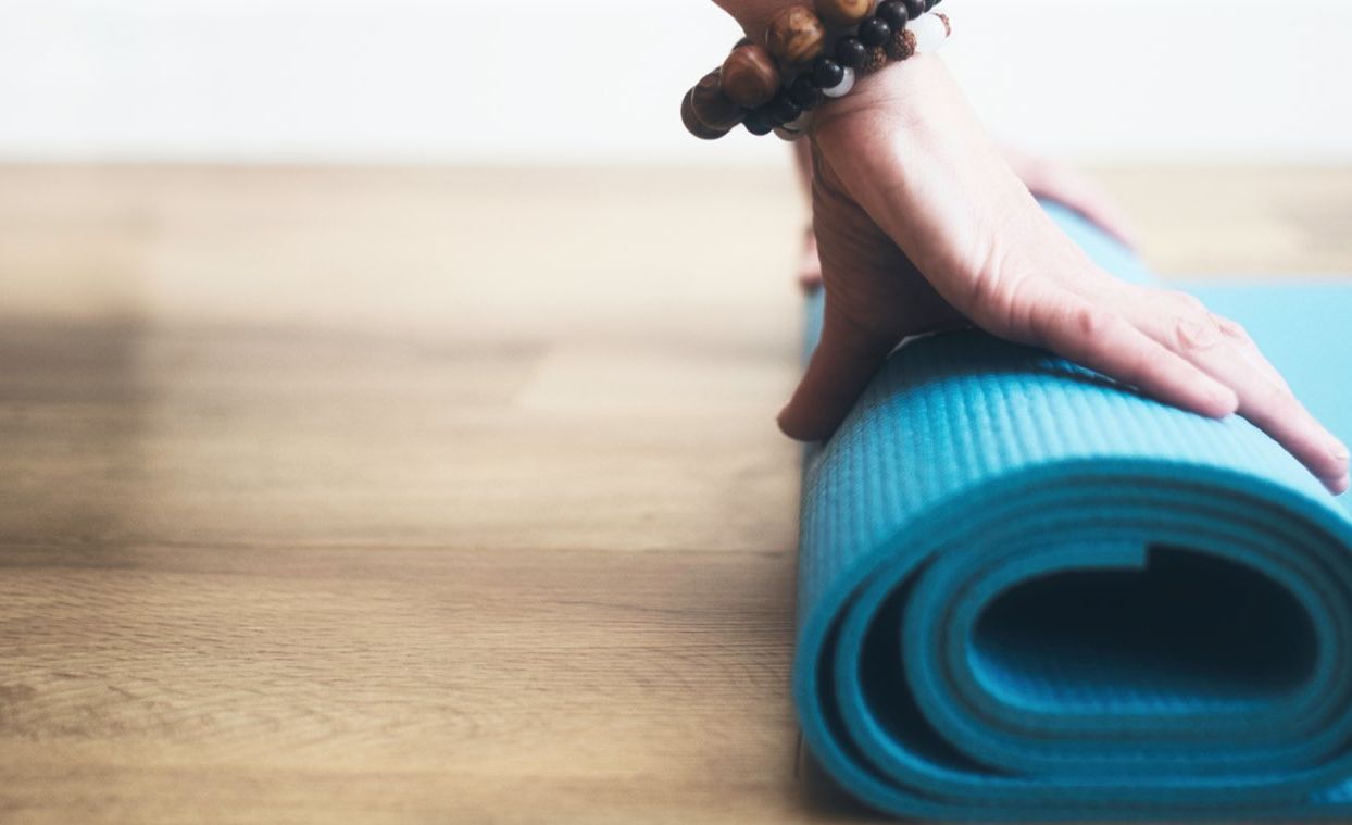 Woman rolling her pilates matt out on the floor.
